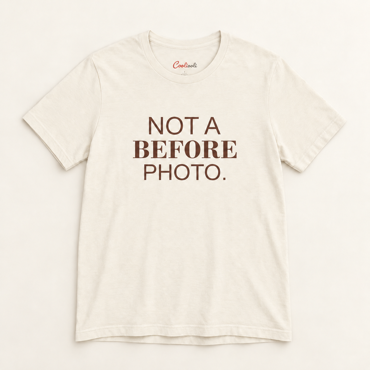 NOT A BEFORE PHOTO. Bella+Canvas 3001 tee in Natural, overhead view on a plain warm neutral studio background