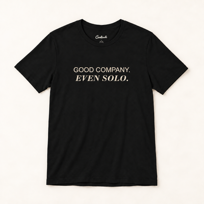 GOOD COMPANY. EVEN SOLO. Bella+Canvas 3001 tee in Black, overhead view on a plain warm neutral studio background