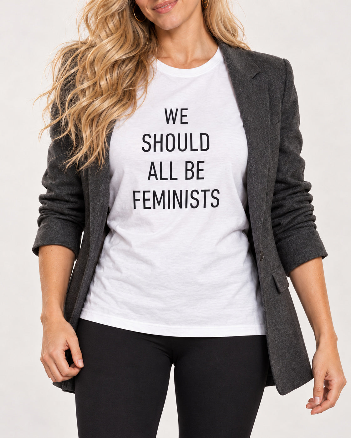 White We Should All Be Feminists Bella+Canvas 3001 tee: full-print collar-to-hip detail, styled with black leggings and an open blazer.