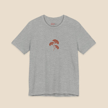 Athletic Heather Bella+Canvas 3001 T-shirt with an original small rust three-leaf ginkgo twig graphic.