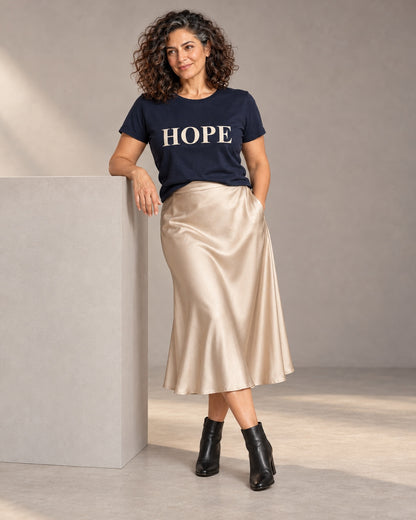 Leila wearing the Navy HOPE Bella+Canvas 3001 tee with a satin midi skirt and black ankle boots, full-length studio portrait.