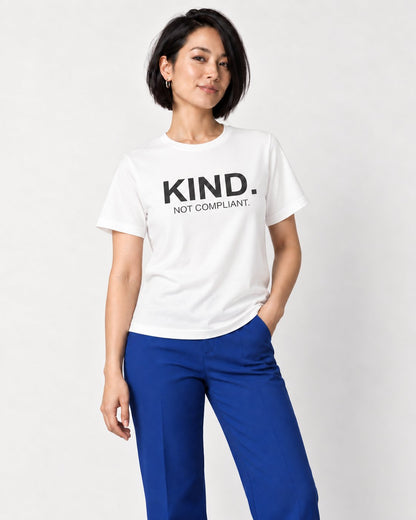 Mina wearing the Kind. Not Compliant. affirmation tee in White with cobalt trousers and burgundy heels