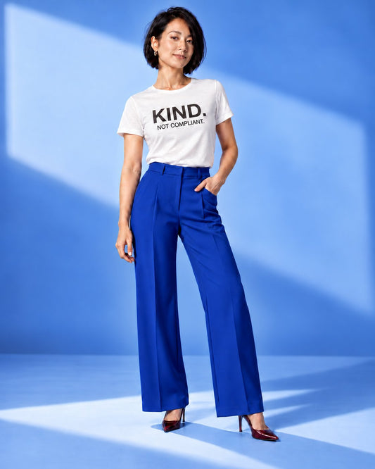 Mina wearing the Kind. Not Compliant. affirmation tee in White with cobalt trousers and burgundy heels