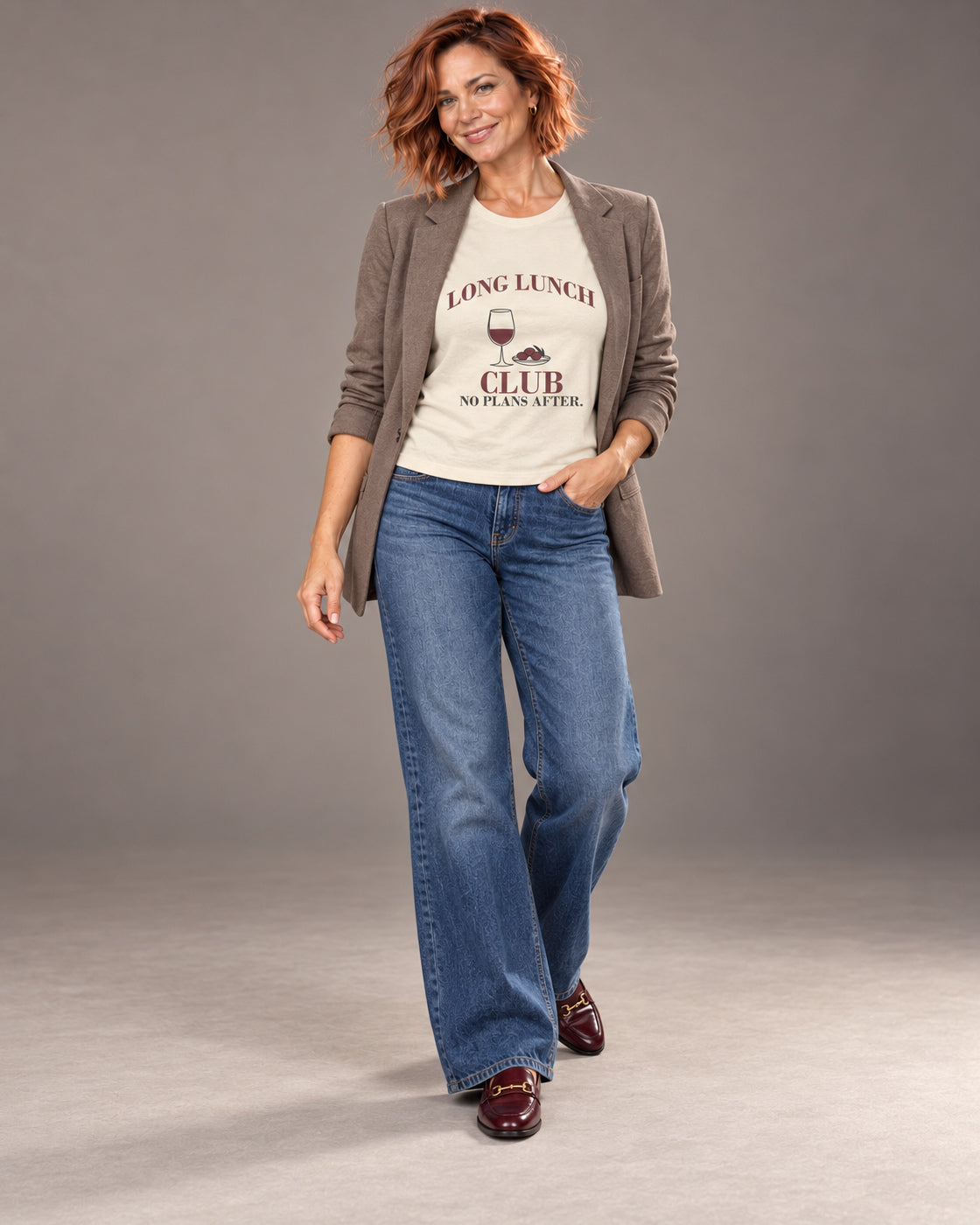 Sienna wearing the Natural Long Lunch Club Bella+Canvas 3001 tee with wide-leg jeans and a relaxed blazer in a full-length professional studio photograph.