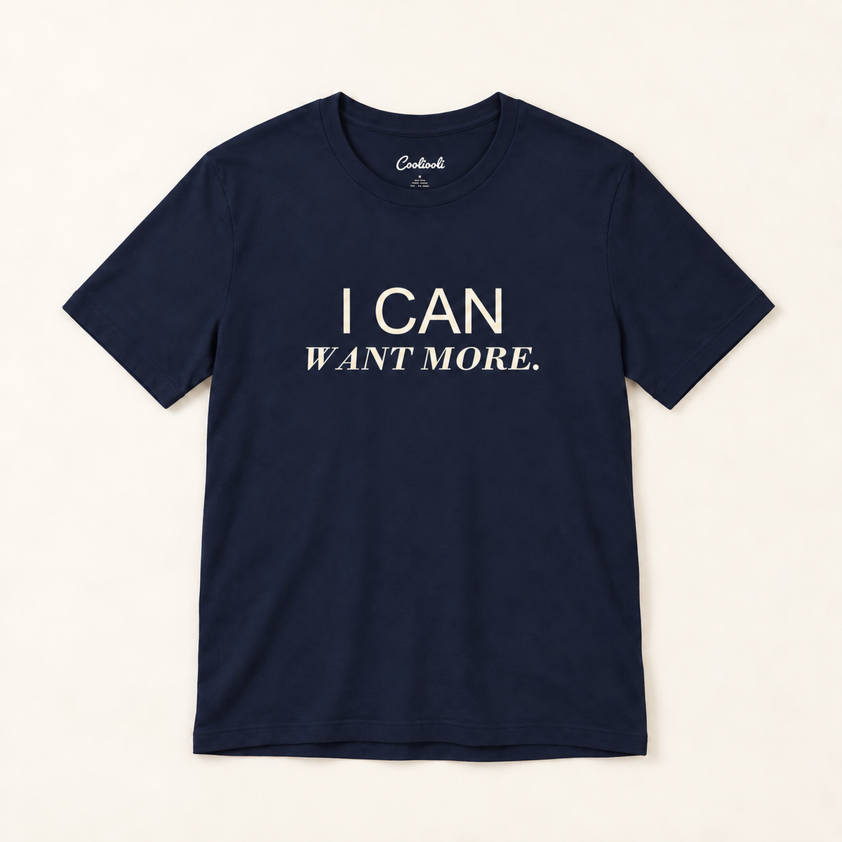 I CAN WANT MORE. Bella+Canvas 3001 tee in Navy, overhead view on a plain warm neutral studio background