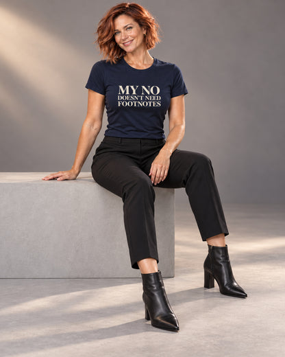 Sienna wearing the navy My No Doesn’t Need Footnotes Bella+Canvas 3001 tee with tailored black trousers and heeled ankle boots, seated during a professional studio photoshoot.