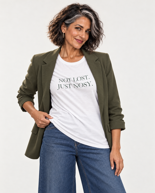 Freya wearing the white Not Lost. Just Nosy. Bella+Canvas3001 T-shirt with an open olive blazer and indigo jeans.