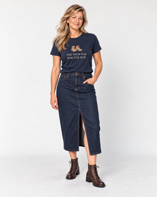 Elena wearing the Navy The Walk Was for the Pub hiking boots T-shirt with an indigo denim midi skirt and brown lace-up ankle boots.