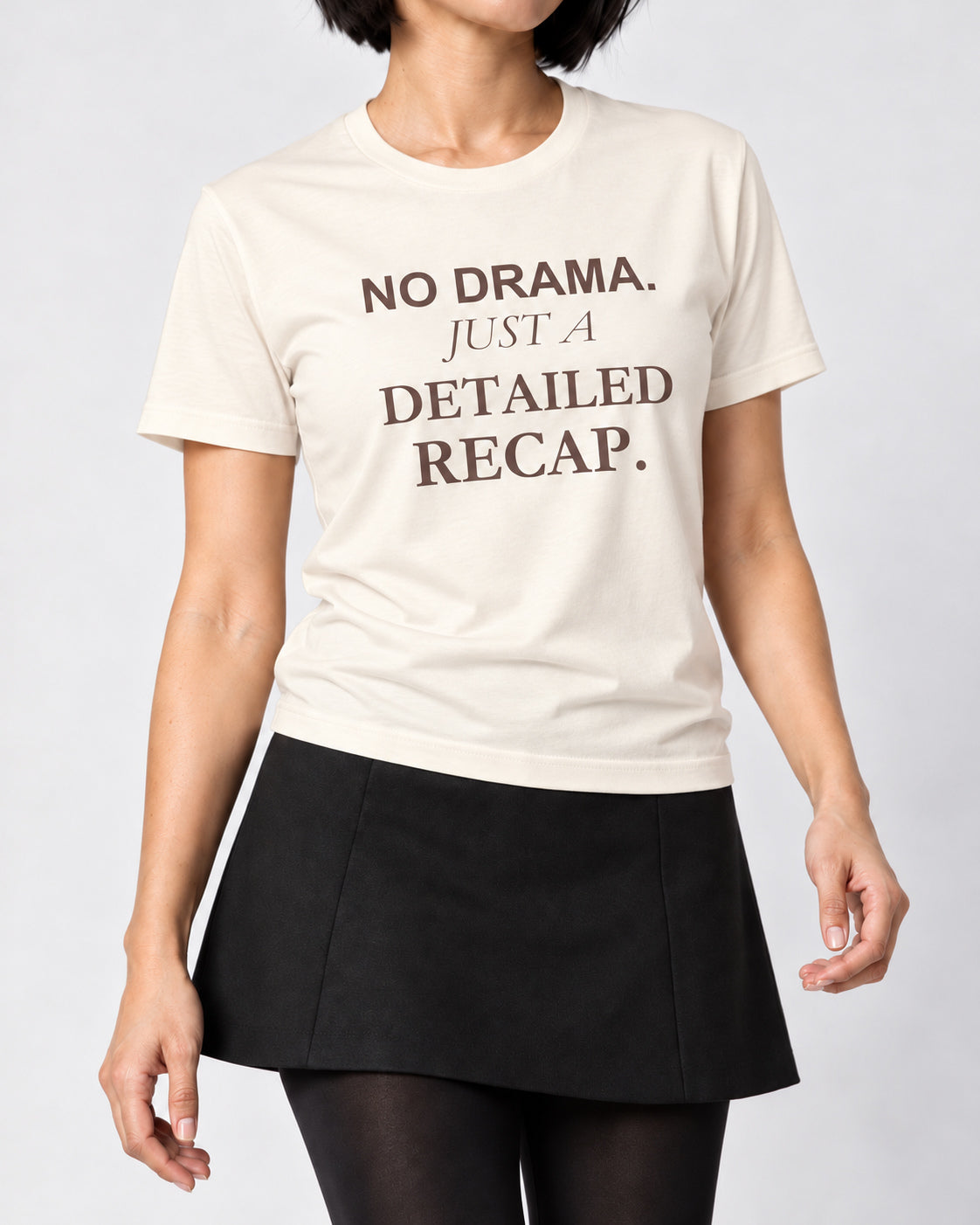 Mina wearing the Natural NO DRAMA. JUST A DETAILED RECAP. Bella+Canvas 3001 tee — collar-to-hip studio detail with print following fabric folds