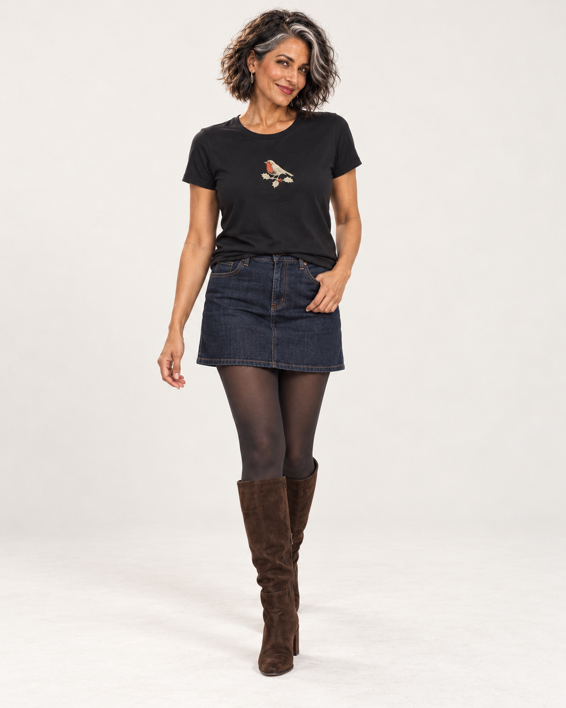Freya wearing the Black robin and holly Christmas T-shirt with a denim mini skirt, opaque tights and tall brown suede boots.