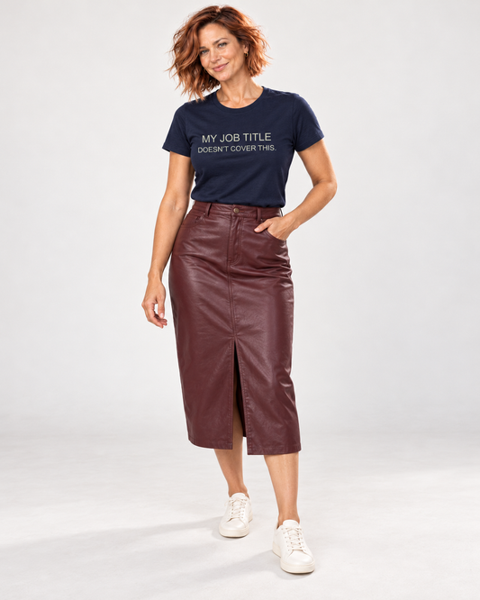 Sienna wearing the Navy My Job Title Doesn’t Cover This T-shirt with a burgundy leather-look midi skirt and cream trainers in the pale studio.