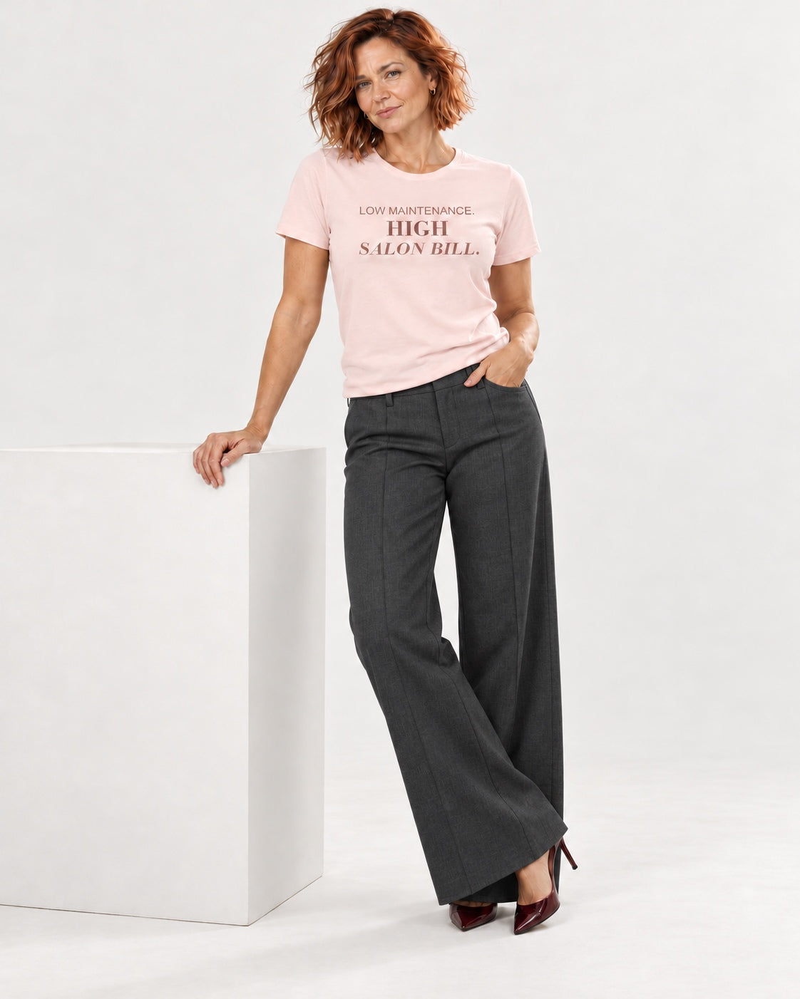 Sienna wearing the Soft Pink LOW MAINTENANCE. HIGH SALON BILL. Bella+Canvas 3001 tee — full-length natural studio outfit