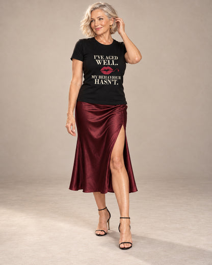 Claudia wearing the Black Vintage. Still Trouble. Bella+Canvas 3001 tee with cream lettering and a burgundy lipstick kiss, styled with a satin midi skirt and heels in a professional studio
