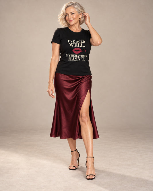 Claudia wearing the Black Vintage. Still Trouble. Bella+Canvas 3001 tee with cream lettering and a burgundy lipstick kiss, styled with a satin midi skirt and heels in a professional studio