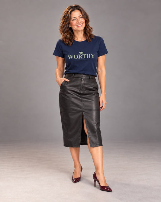 Sophie wearing the Navy Worthy Bella+Canvas 3001 T-shirt with a black leather midi skirt and burgundy pointed heels, standing in a relaxed pose during a professional studio photoshoot.